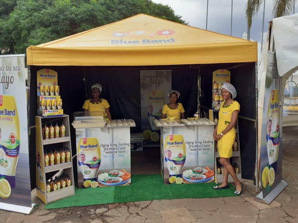 A Blue Band gazebo with two fully stocked product shelves and three uniformed promoters