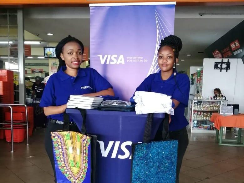 A branded VISA counter in a supermarket with two ambassadors behind it