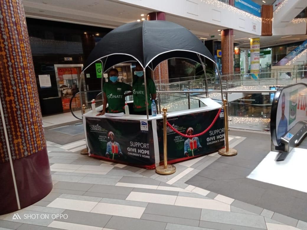 A black branded gazebo and rope line inside a shopping centre
