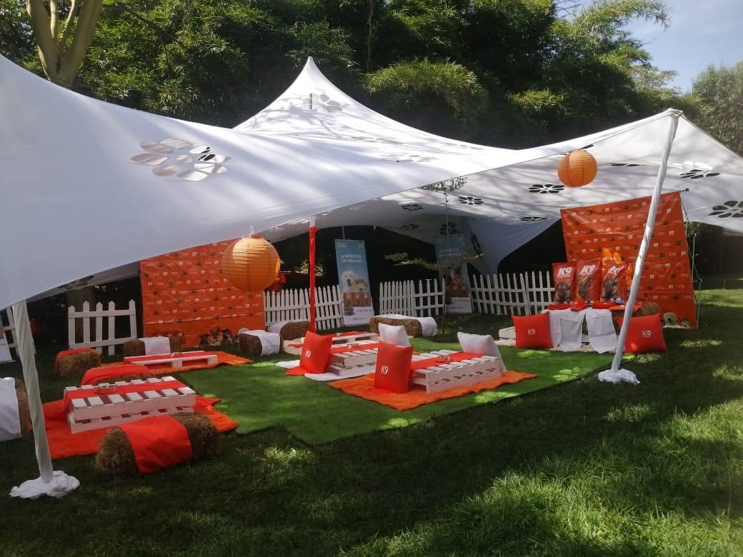 White stretch tents over red furniture and picket fencing on a lawn